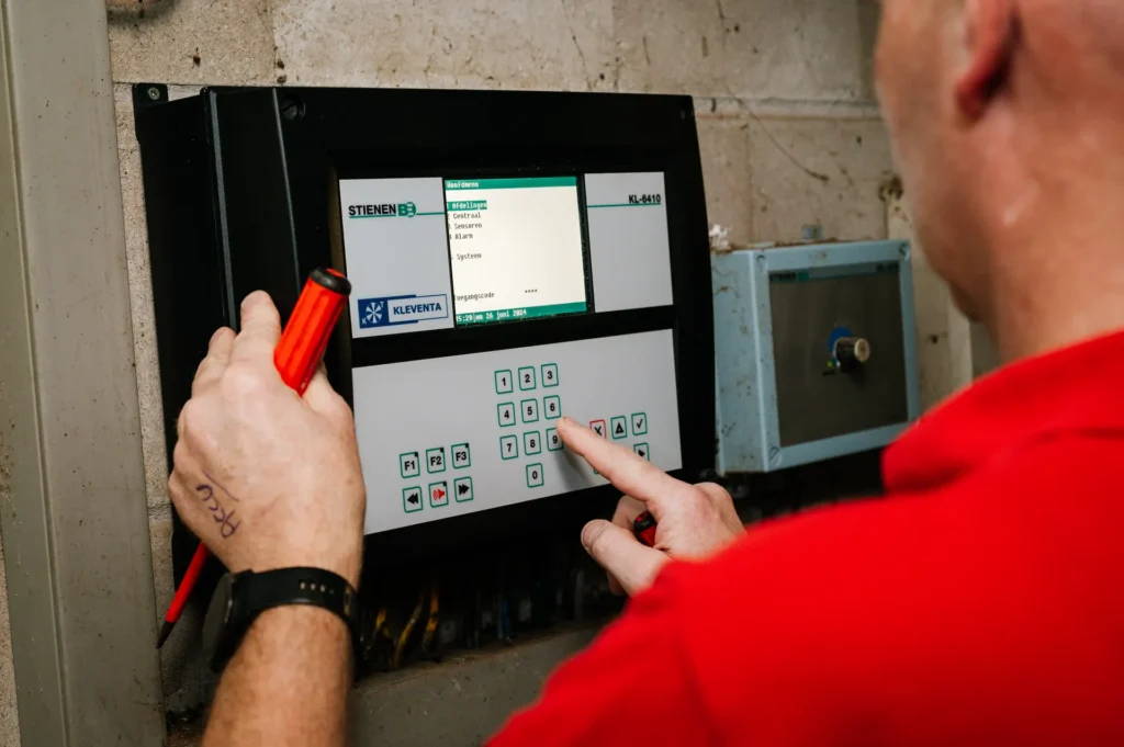 Monteur stelt een klimaatcomputer voor de stal in