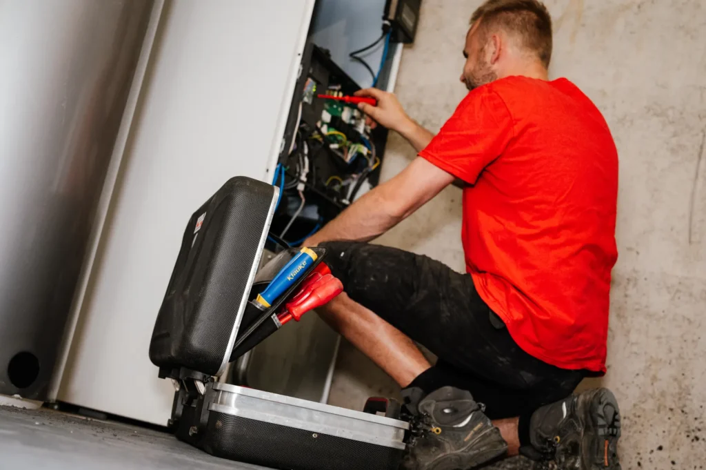 Monteur met gereedschapskoffer aan het werk bij een installatie