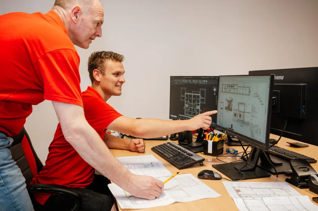 Twee medewerkers bespreken een installatietekening op de computer