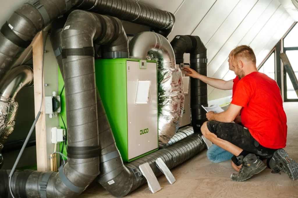 Monteur sluit een ventilatie-unit met warmteterugwinning aan op zolder