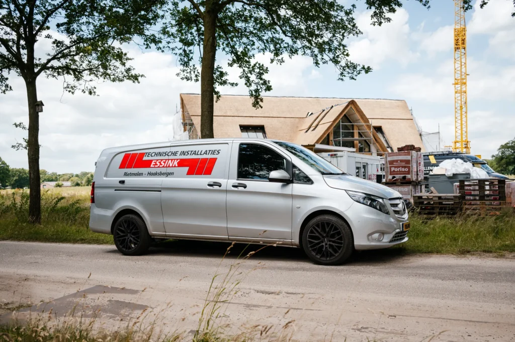 Bedrijfsbus van Essink bij een woning in aanbouw